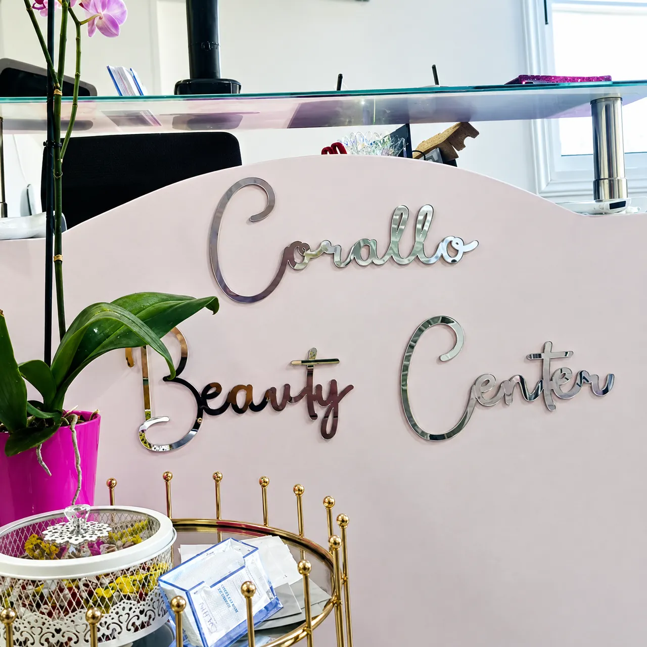 The mirrored Corallo Beauty Center lettering on the reception desk, with an orchid